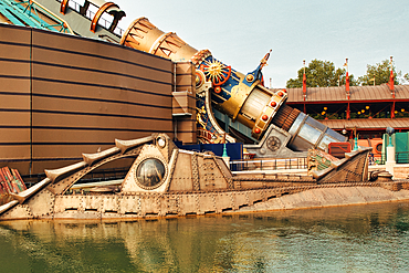 Image shows a steampunk submarine in water, adjacent to a building and a large golden telescope structure at Disneyland Paris, France.
