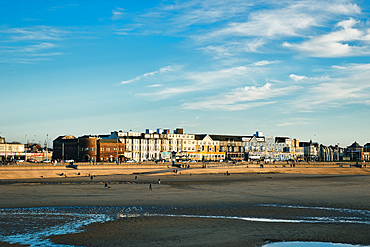 Coastal town skyline with buildings overlooking a sandy beach under a clear blue sky in Blackpool, England