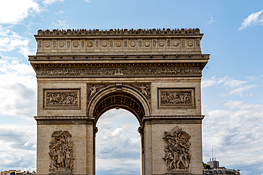 Close-up of the Arc de Triomphe in Paris, showcasing its architectural details, sculptures, and the people viewing from the top.