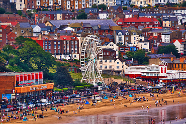 A coastal town with a beach, Ferris wheel, and numerous buildings of various heights and colors in Scarborough, UK.