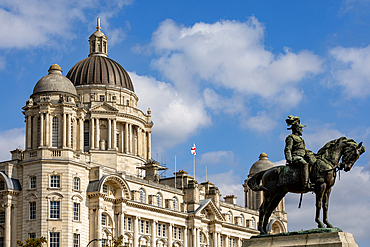 A majestic building with domes and columns stands against a blue sky with clouds, while a bronze equestrian statue is in the foreground in Liverpool, UK.