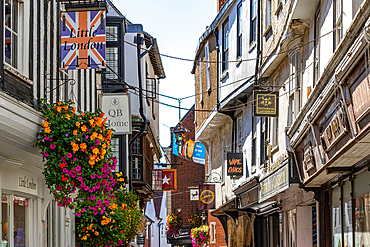 Quaint street with traditional buildings and hanging flower baskets, under a clear blue sky in Canterbury, Kent, England, United Kingdom, Europe