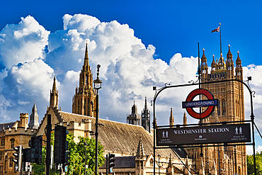 London's iconic Westminster Station, featuring the Houses of Parliament and the Union Jack against a dramatic blue sky with fluffy white clouds.