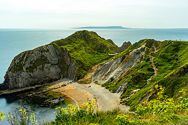 Scenic view of a coastal landscape with cliffs, beach, and a winding path leading to the sea at Durdle Door, Jurassic Coast, UNESCO World Heritage Site, Dorset, England, United Kingdom, Europe