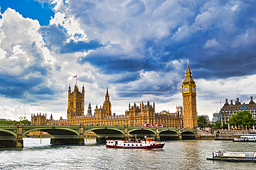 London's iconic Parliament buildings and Big Ben stand prominently along the Thames, with a tour boat passing under Westminster Bridge under a dramatic sky.