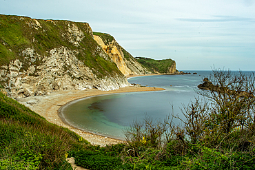 Scenic view of a tranquil cove with a sandy beach, surrounded by rugged cliffs under a clear blue sky at Durdle Door, Jurassic Coast, UNESCO World Heritage Site, Dorset, England, United Kingdom, Europe