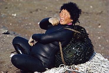 A woman diver or Haenyow with plastic float, diving for urchins, clams, shellfish and edible seaweed, on Songsan Beach on Cheju Island, South Korea, Asia 