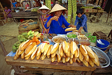 Woman street vendor selling French bread sandwiches from her stall on the pavement in Nhatrang, Vietnam, Indochina, Southeast Asia, Asia