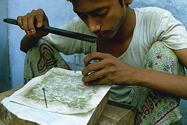 Tapping out the block print design through a stencil, from which the carver will work, India, Asia