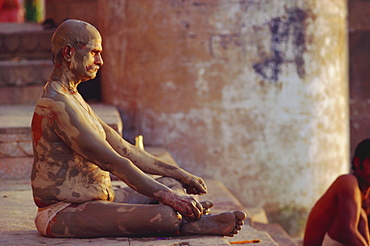 Hindu pilgrim meditating, sitting cross-legged on the Ghats, Varanasi (Benares), Uttar Pradesh State, India