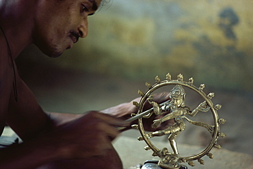 Man finishing off image of the dancing Siva, brass moulding workshop, India, Asia