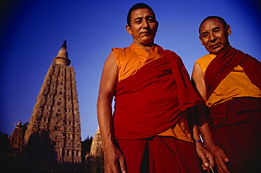 Two Tibetan monks with the main Mahabodhi temple in the background, Bodh Gaya, Bihar state, India, Asia