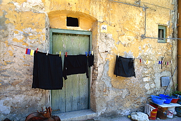 Clothes on a washing line outside an old house with peeling walls at Corleone on the island of Sicily, Italy, Europe