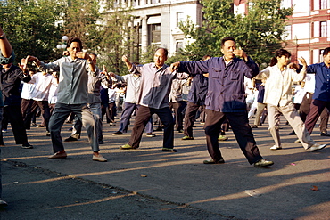 A group of men and women doing tai-chi exercises in the open air on the Bund in Shanghai, China, Asia