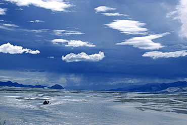 Puffy white clouds over a river and hills