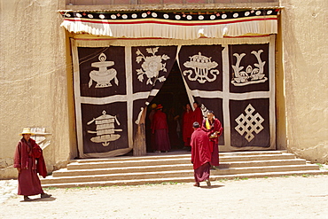 Lamas at monastery entrance, which is covered with a curtain depicting the sacred symbols of Buddhism, at Longki, south of Yushu in Qinghai, China, Asia