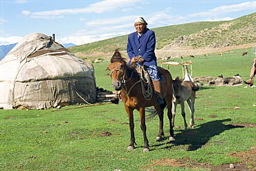 Kazak woman on horseback beside a yurt in the Altay mountains, north east Xinjiang, China, Asia