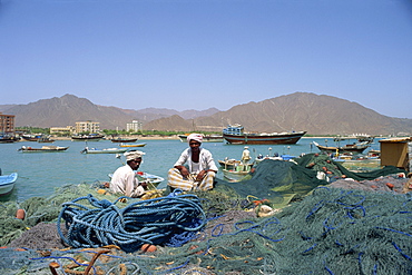 Men sitting amongst fishing nets at dockside, Fujairah Sheikdom, Khor Fakkan, United Arab Emirates, Middle East