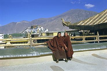 Two Tibetan Buddhist monks at Jokhang temple, with the Potala palace behind, Lhasa, Tibet, China, Asia