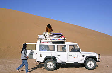 Loading equipment on a 4x4 vehicle after desert trek, Chigaga dunes, Draa Valley, Morocco, North Africa, Africa