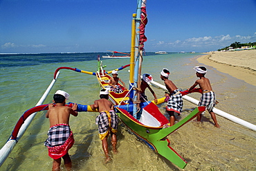 Men launching an outrigger fishing boat from Sanur Beach on the island of Bali, Indonesia, Southeast Asia, Asia