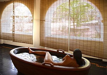 Girl inside the wooden bathtub at the Spa at Kalari Kovilakom, Kerala, India, Asia