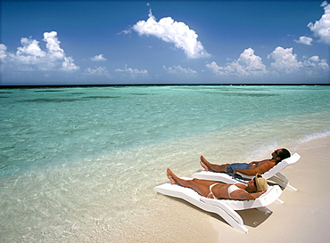 Couple sunbathing on a beach, Maldives, Indian Ocean, Asia