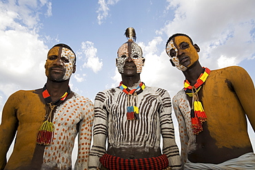 Three Karo tribesmen with face and body decoration in chalk, imitating the spotted plumage of the guinea fowl, Omo river, Lower Omo Valley, Ethiopia, Africa