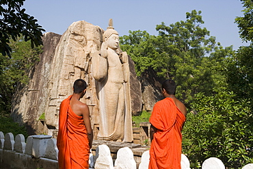 Buddhist monks in front of the giant standing statue of the Buddha dating from the 5th century, Aukana, Sri Lanka, Asia