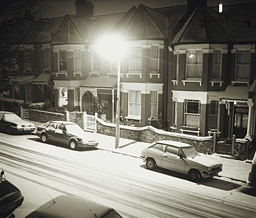 Cars and houses on snow covered street at night in winter, England, United Kingdom, Europe