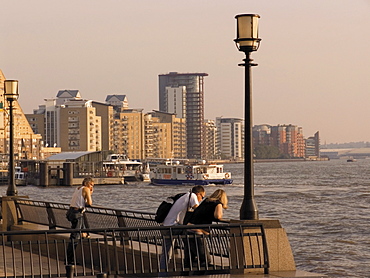 People looking at River Thames, with modern riverside flats beyond, the Canary riverside walk, Docklands, London, England, United Kingdom, Europe