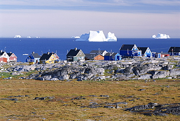 Painted village houses in front of icebergs in Disko Bay, Oeqertarsuaq (Godhavn), Disko island, west coast, Greenland, Polar Regions