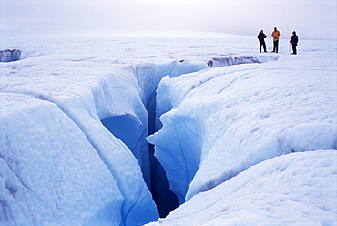 Canyon cut by meltwater stream, before sinking into moulin beside hikers, on icecap above Disko Bay on the west coast, Greenland, Polar Regions