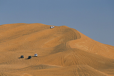 Tourists dune-bashing in 4 wheel drive vehicles in desert inland from city, Dubai, United Arab Emirates, Middle East