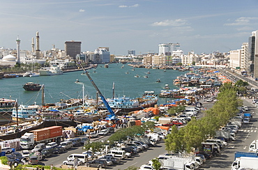 Dhows moored for unloading alongside Deira wharves, minarets of the Grand Mosque in Buer Dubai on right of creek, Dubai Creek, Dubai, United Arab Emirates.