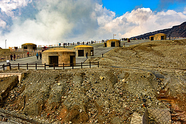Nakadake volcano within Aso caldera, Kyushu, Japan; bomb shelters for safety during sudden eruptions from steaming crater in background.