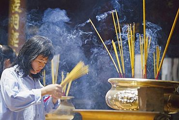 Woman with incense inside a temple, Ho Chi Minh City (Saigon), Vietnam, Indochina, Asia