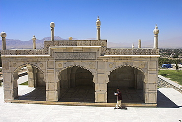 Man reading the Koran whilst walking round the white marble Mosque built by Shah Jahan, Gardens of Babur, Kabul, Afghanistan, Asia