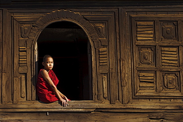 Novice monk sitting in window of 18th century wooden monastery of Nat Taung Kyaung (May-taung taik) thought to be the oldest wooden monastery in the area, Bagan (Pagan), Myanmar (Burma), Asia