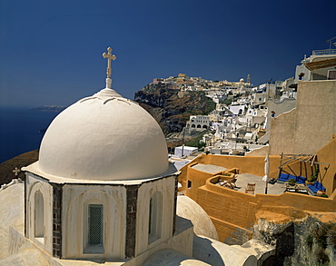 The white dome of a chapel and an ochre painted balcony, with the houses of Fira Town behind, Santorini (Thira), Cyclades Islands, Greek Islands, Greece, Europe