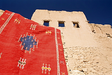 Red carpet drying in the sun, with mud house behind, Kasbah Ait Benhaddou, near Ouarzazate, Morocco, North Africa, Africa