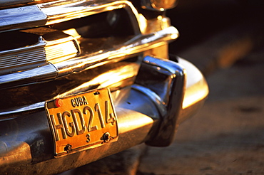 Close-up of chrome bumper and yellow car number plate in morning light, Havana, Cuba, West Indies, Central America