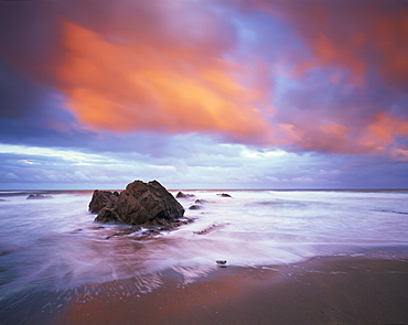 Widemouth Bay at sunrise, with offshore rocks and red storm clouds overhead, near Bude, Cornwall, England, United Kingdom, Europe