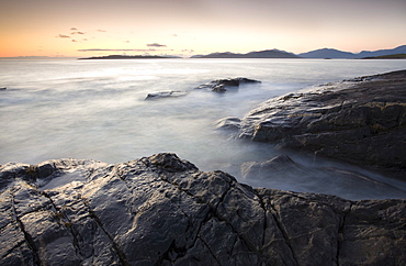 Dusk view across open water towards Taransay and North Harris from the rocky shore at Borve, Isle of Harris, Outer Hebrides, Scotland, United Kingdom, Europe