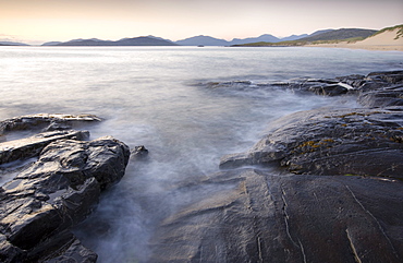 Dusk view across open water towards Taransay and North Harris from the rocky shore at Borve, Isle of Harris, Outer Hebrides, Scotland, United Kingdom, Europe