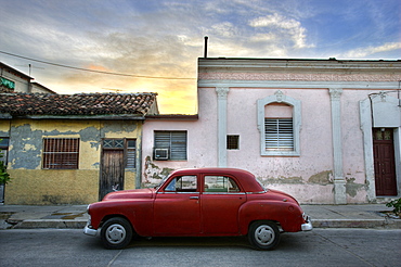 Classic red American car parked outside houses at sunset, Cienfuegos, Cuba, West Indies, Central America