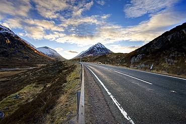 A82 trunk road heading across Rannoch Moor towards Glencoe with snow-covered mountains in distance and dramatic evening sky, Rannoch Moor, near Fort William, Highland, Scotland, United Kingdom, Europe