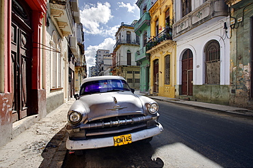 Old American Plymouth car parked on deserted street of old buildings, Havana Centro, Havana, Cuba, West Indies, Caribbean, Central America