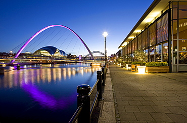 View along Newcastle Quayside at night showing the River Tyne, the floodlit Gateshead Millennium Bridge, the Arched Bridge and the Sage Gateshead, Newcastle-upon-Tyne, Tyne and Wear, England, United Kingdom, Europe