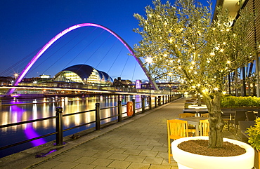 View along Newcastle Quayside at night showing the River Tyne, the floodlit Gateshead Millennium Bridge and the Sage Gateshead, Newcastle-upon-Tyne, Tyne and Wear, England, United Kingdom, Europe